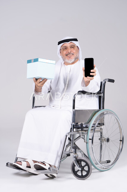 رجل إماراتي على كرسي متحرك يحمل هدية وجوال