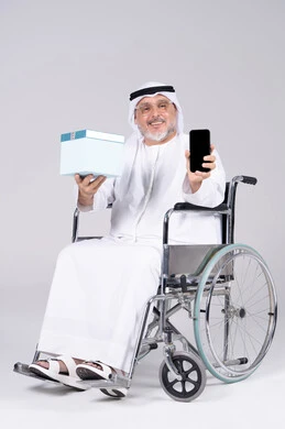 رجل إماراتي على كرسي متحرك يحمل هدية وجوال