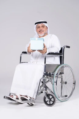 رجل إماراتي مسن على كرسي متحرك يحمل هدية