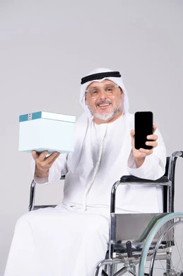 رجل إماراتي على كرسي متحرك يحمل هدية وهاتف