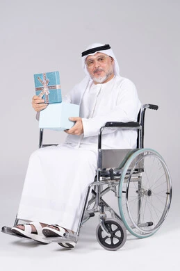 رجل إماراتي مسن على كرسي متحرك يحمل هدية