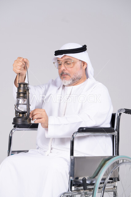 رجل إماراتي مسن على كرسي متحرك مع فانوس تراثي
