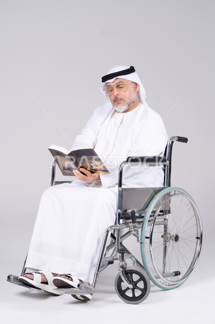 رجل إماراتي مسن على كرسي متحرك يقرأ كتاب