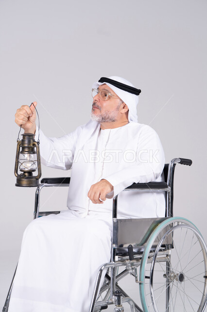 رجل إماراتي على كرسي متحرك يحمل فانوس تقليدي