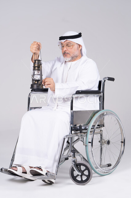 رجل إماراتي مسن على كرسي متحرك يحمل فانوساً