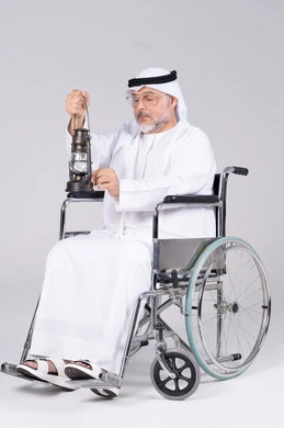 رجل إماراتي مسن على كرسي متحرك يحمل فانوساً