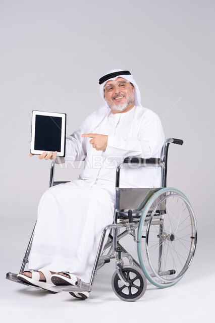 رجل إماراتي على كرسي متحرك يحمل جهاز لوحي