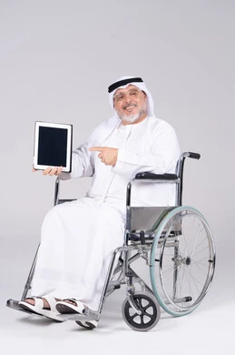 رجل إماراتي على كرسي متحرك يحمل جهاز لوحي