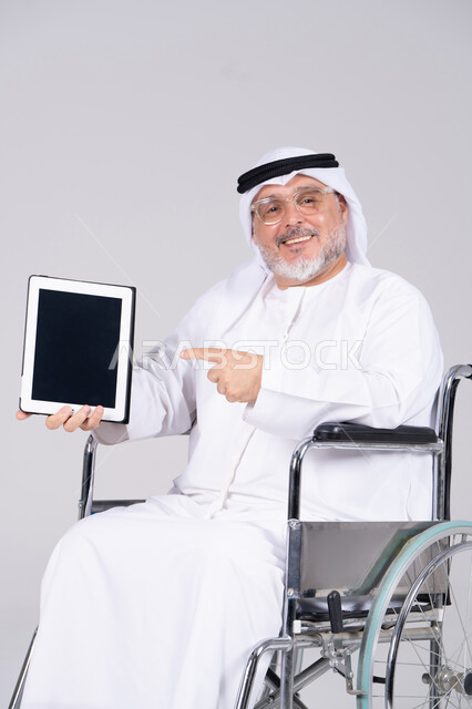 رجل إماراتي على كرسي متحرك يحمل جهاز لوحي