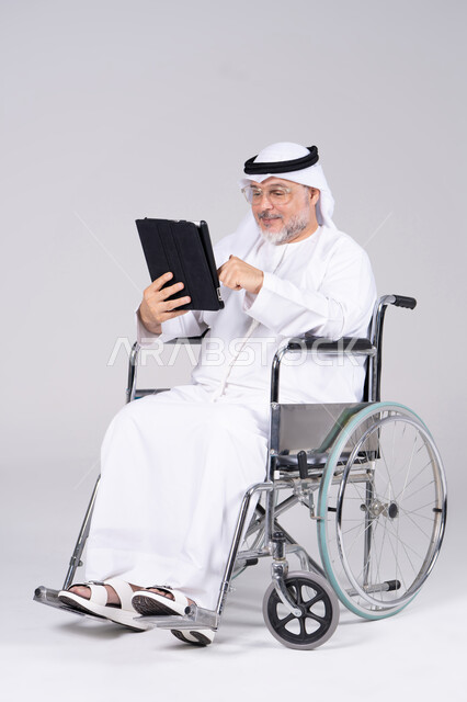 رجل إماراتي على كرسي متحرك يستخدم جهاز لوحي