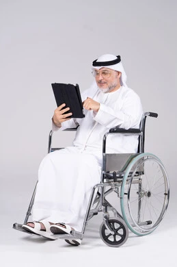 رجل إماراتي على كرسي متحرك يستخدم جهاز لوحي