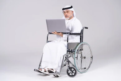 Emirati Senior Man in Wheelchair Using Laptop White Background