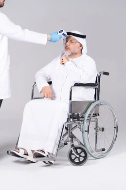 قياس درجة حرارة رجل إماراتي مسن على كرسي متحرك