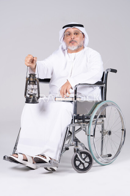 رجل إماراتي مسن على كرسي متحرك يحمل فانوساً