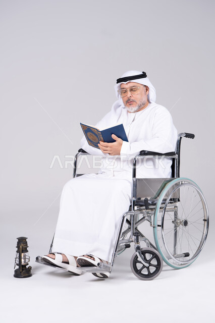رجل إماراتي مسن على كرسي متحرك يقرأ القرآن الكريم
