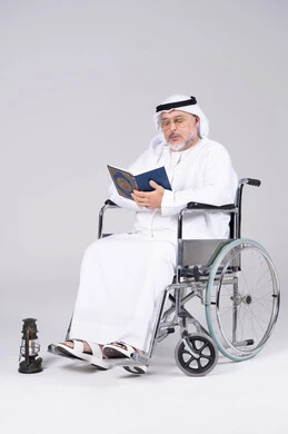 رجل إماراتي مسن على كرسي متحرك يقرأ القرآن الكريم