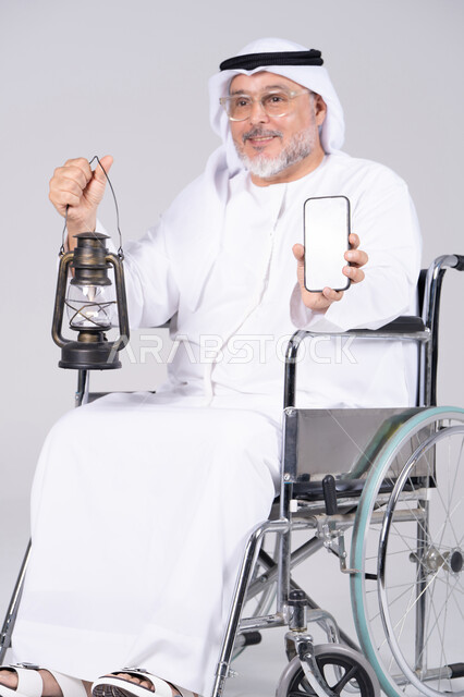 رجل إماراتي مسن على كرسي متحرك مع فانوس وهاتف