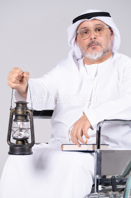 رجل إماراتي مسن على كرسي متحرك يحمل فانوساً