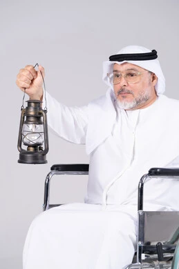 رجل إماراتي مسن على كرسي متحرك يحمل فانوسا