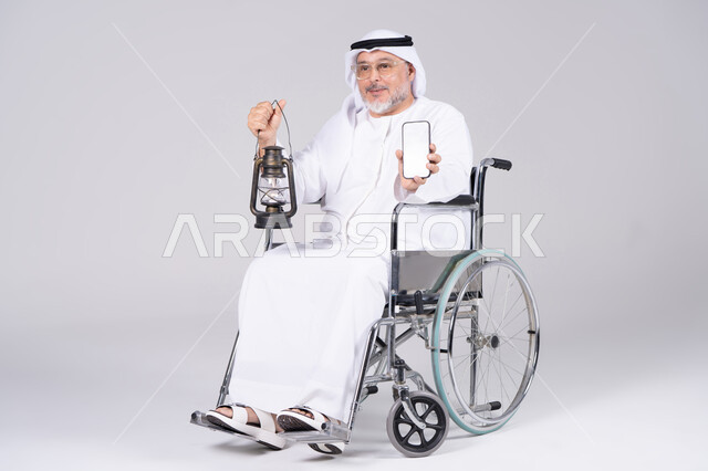 رجل إماراتي على كرسي متحرك يحمل فانوس وهاتف