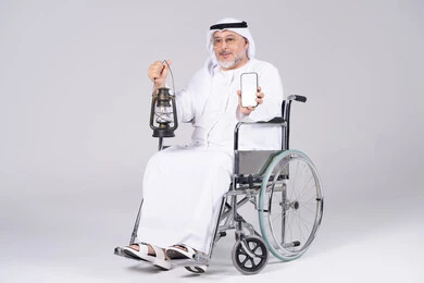 رجل إماراتي على كرسي متحرك يحمل فانوس وهاتف