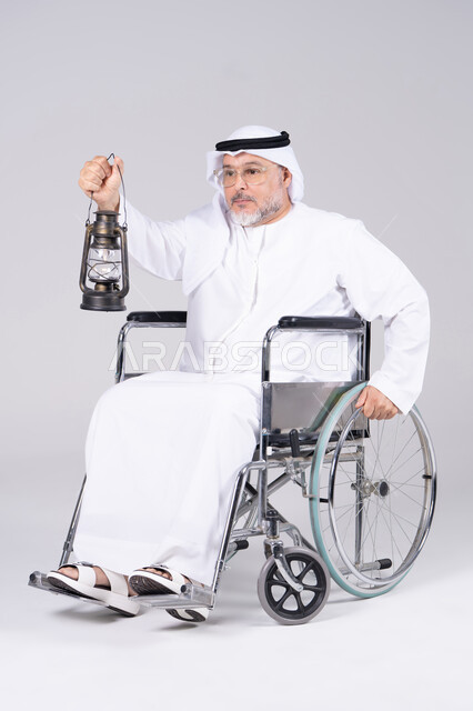 رجل إماراتي على كرسي متحرك يحمل فانوس تقليدي