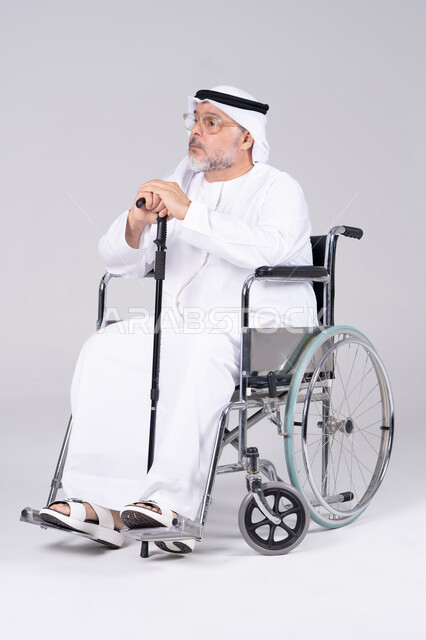 رجل إماراتي مسن على كرسي متحرك خلفية بيضاء