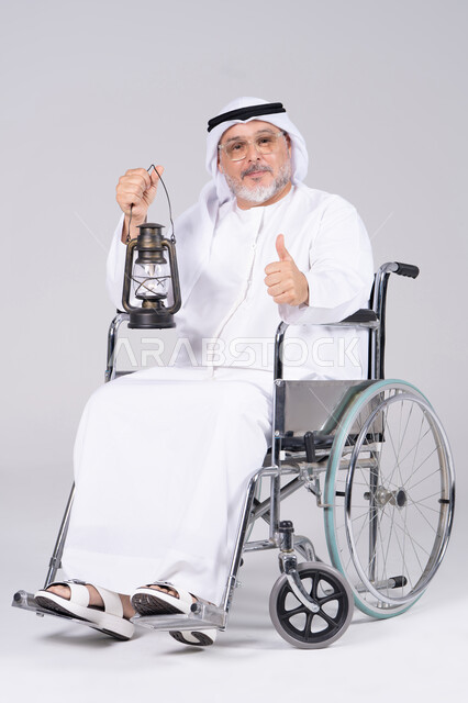 رجل إماراتي مسن على كرسي متحرك يحمل فانوس