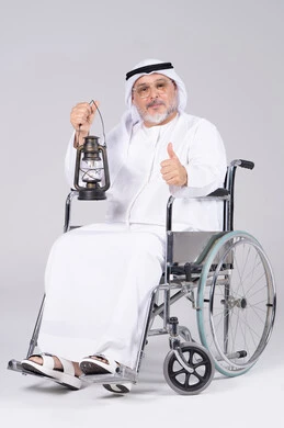 رجل إماراتي مسن على كرسي متحرك يحمل فانوس