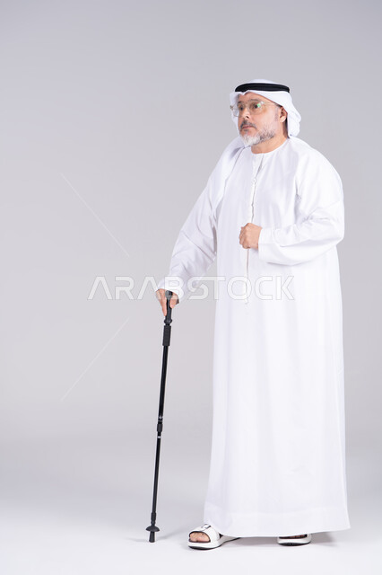 رجل إماراتي مسن مع عصا مشي في الاستوديو