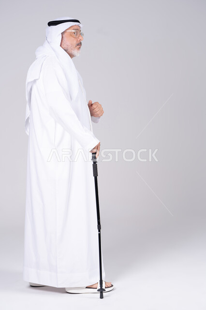 رجل إماراتي مسن مع عصا مشي في الاستوديو
