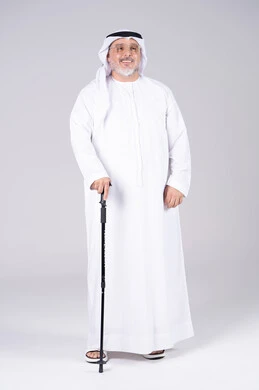 رجل إماراتي مسن يرتدي الزي التقليدي مع عصا مشي في الاستوديو