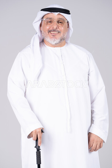 رجل إماراتي مسن بالكندورة التقليدية مع عصا المشي