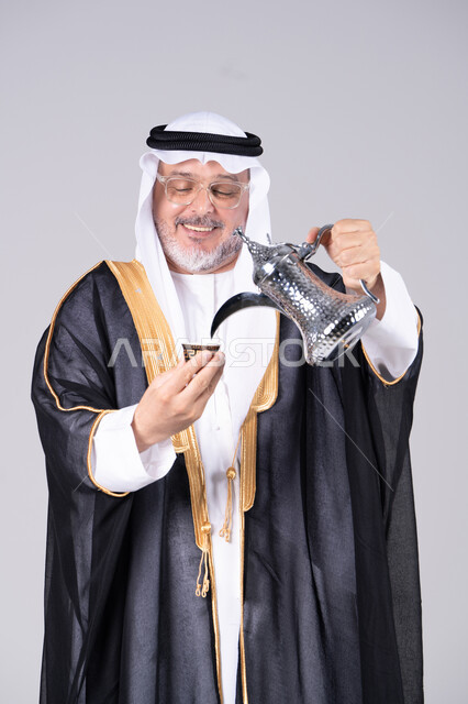 رجل إماراتي يرتدي البشت يصب القهوة العربية