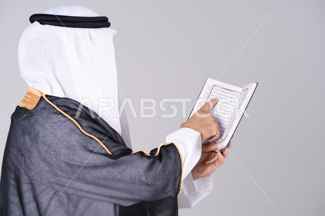 رجل إماراتي بالزي التقليدي يقرأ القرآن الكريم