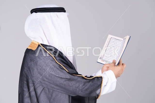 رجل إماراتي يمسك بالقرآن الكريم بالبشت التقليدي