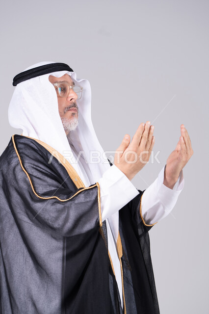 رجل إماراتي بالبشت التقليدي يرفع يديه بالدعاء