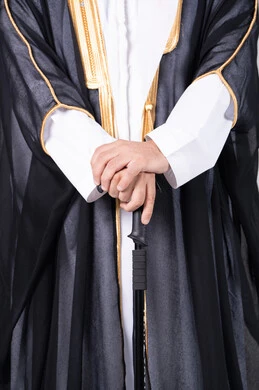 رجل إماراتي بالبشت الأسود التقليدي وعصا المشي