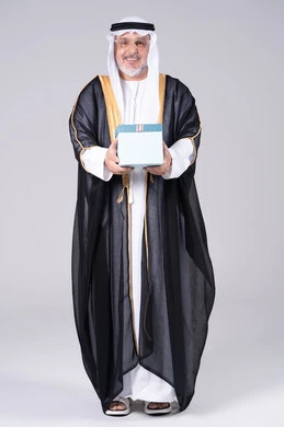 رجل إماراتي بالبشت التقليدي يحمل صندوق هدايا