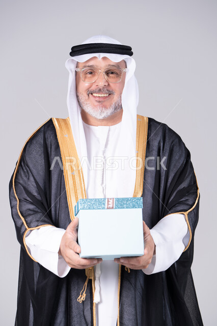 رجل إماراتي يحمل صندوق هدايا في الاستوديو