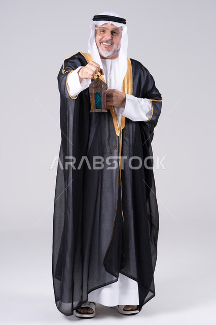 رجل إماراتي بزي البشت التقليدي يمسك فانوس رمضان