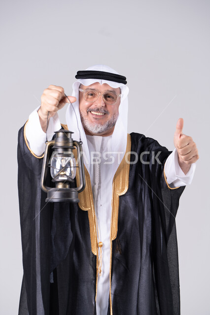 رجل إماراتي بالبشت التقليدي يحمل فانوس زيت
