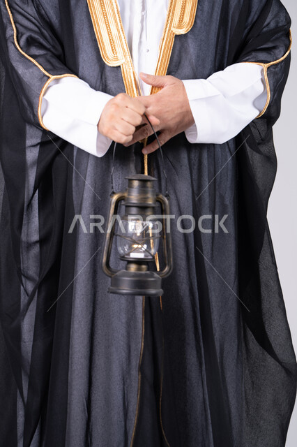 رجل سعودي بالبشت التقليدي يحمل فانوس قديم