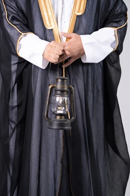 رجل سعودي بالبشت التقليدي يحمل فانوس قديم