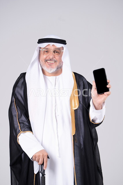Emirati Senior Man in Traditional Dress Holding Smartphone