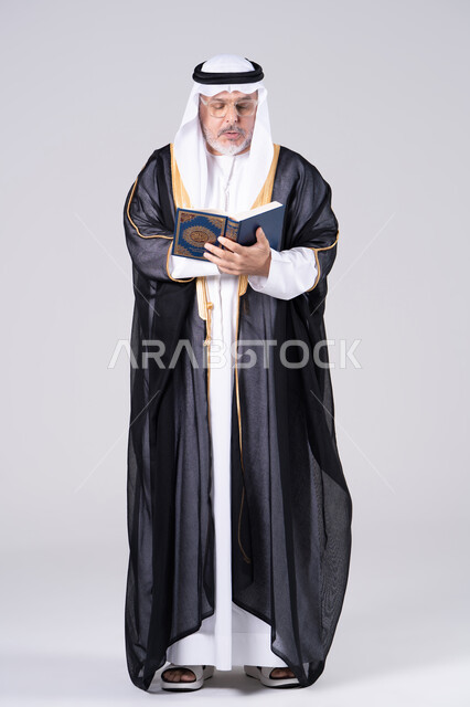 رجل إماراتي مسن بالزي التقليدي يقرأ القرآن الكريم