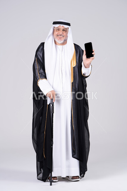 رجل إماراتي بزي البشت يمسك هاتف ذكي