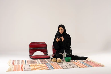 امرأة سعودية تستخدم الجوال في جلسة شعبية