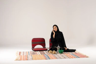 Arab Woman in Abaya Talking on Phone on Traditional Rug Arab Woman in Abaya Talking on Phone on Traditional Rug