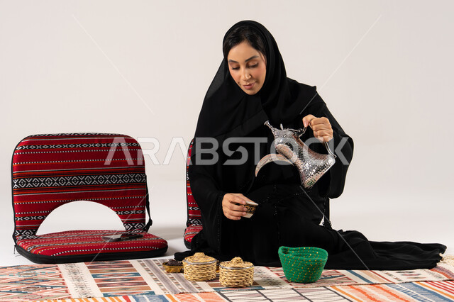 امرأة سعودية تصب القهوة العربية بالدلة والزي التقليدي